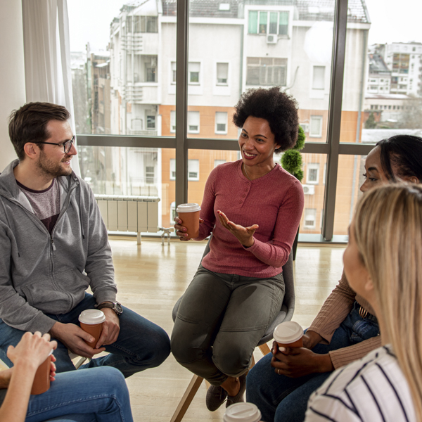 Diverse group of people sitting in circle in group therapy session to promote marketing for therapists.